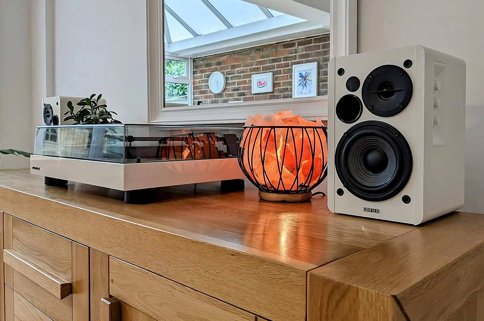 Белые колонки Edifier R1280DBs с проигрывателем в светлой комнате.