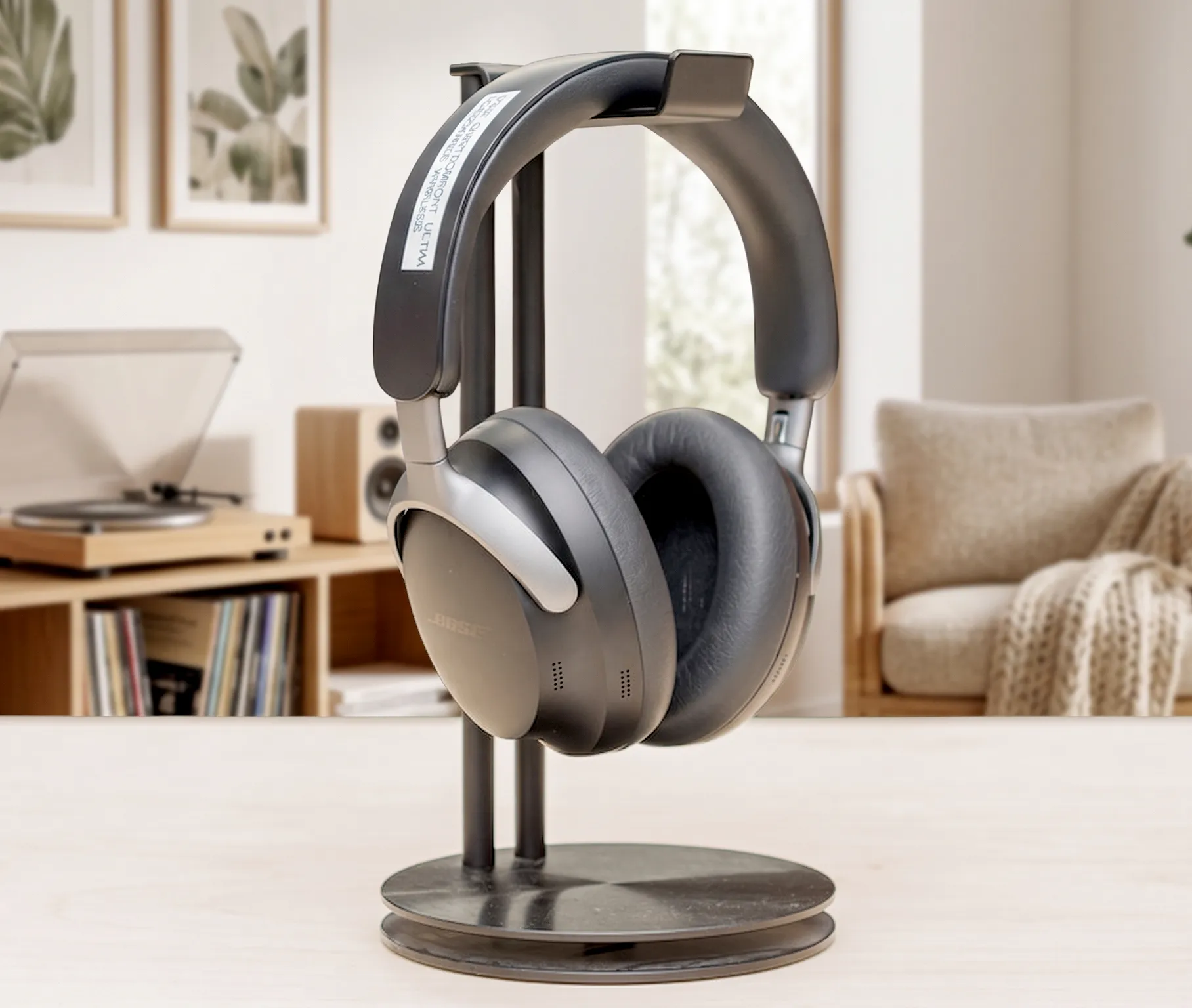 Bose QuietComfort Ultra на черной стойке: вид в три четверти, матовый корпус, фон – размытый интерьер.