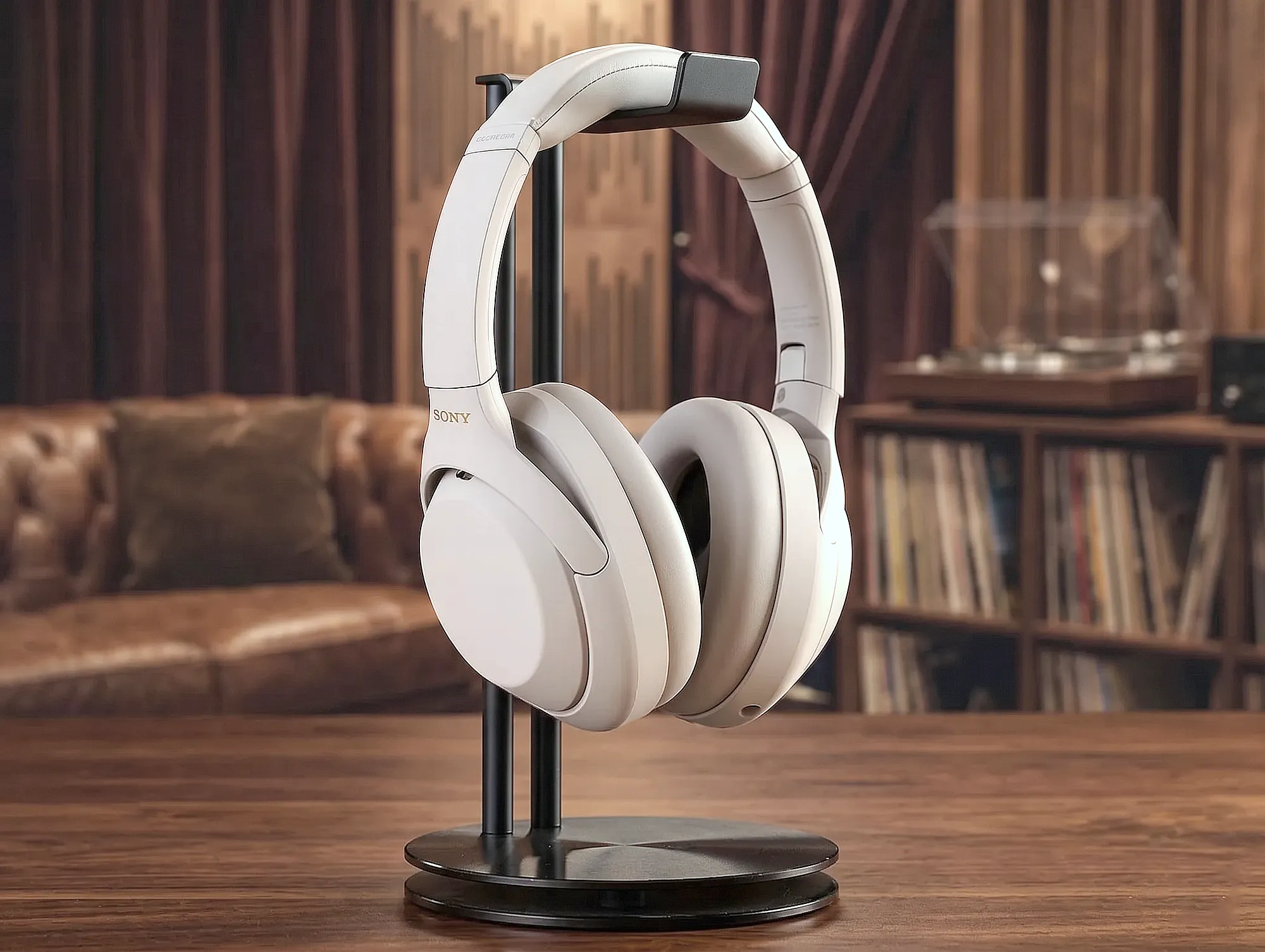 Sony WH-1000XM4 белые наушники на черной стойке, ракурс три четверти, матовый корпус, фон – размытие интерьера.
