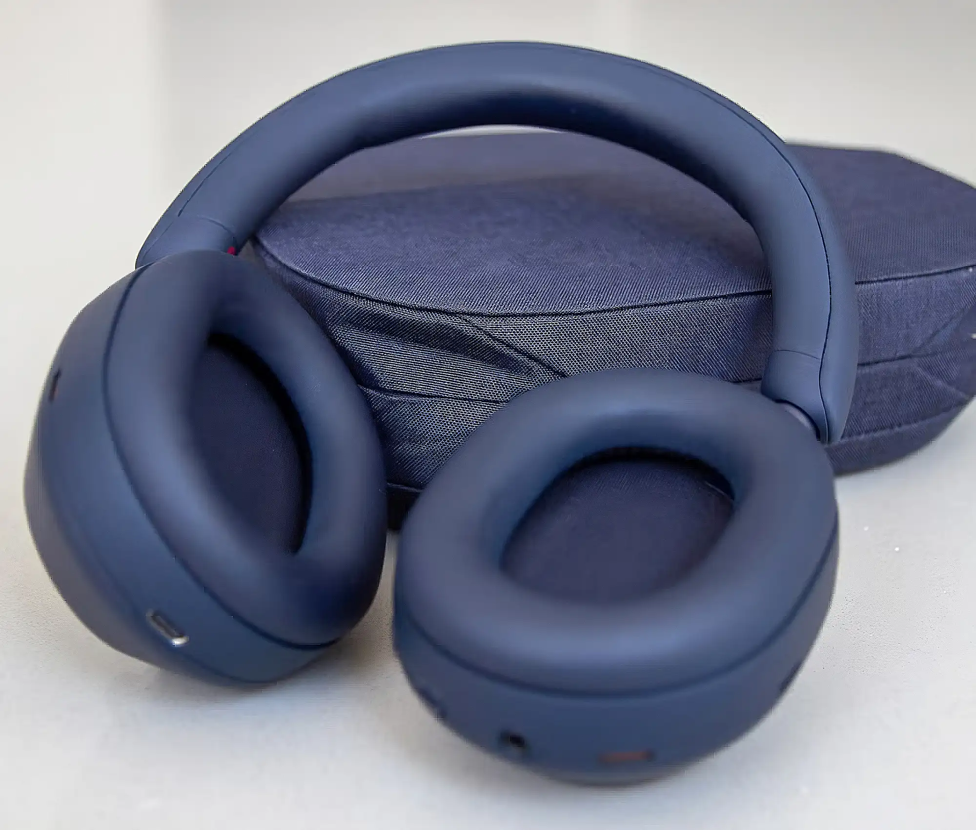 Sony WH-1000XM5 на фоне кейса: кожаные амбушюры и матовое оголовье, темно-синий цвет, вид сверху.