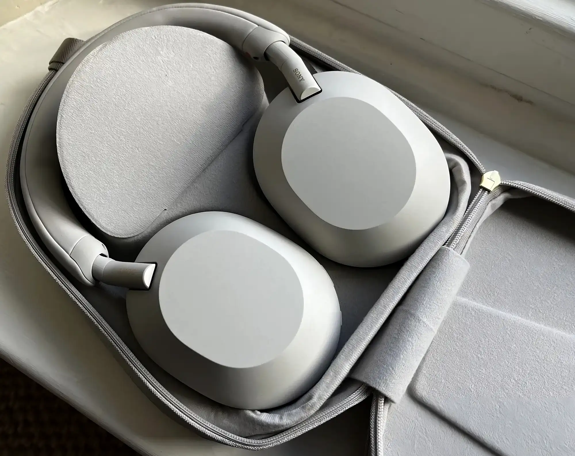 Sony WH-1000XM5 в открытом кейсе: чашки на тканевой подкладке, вид сверху, матовый серый пластик.