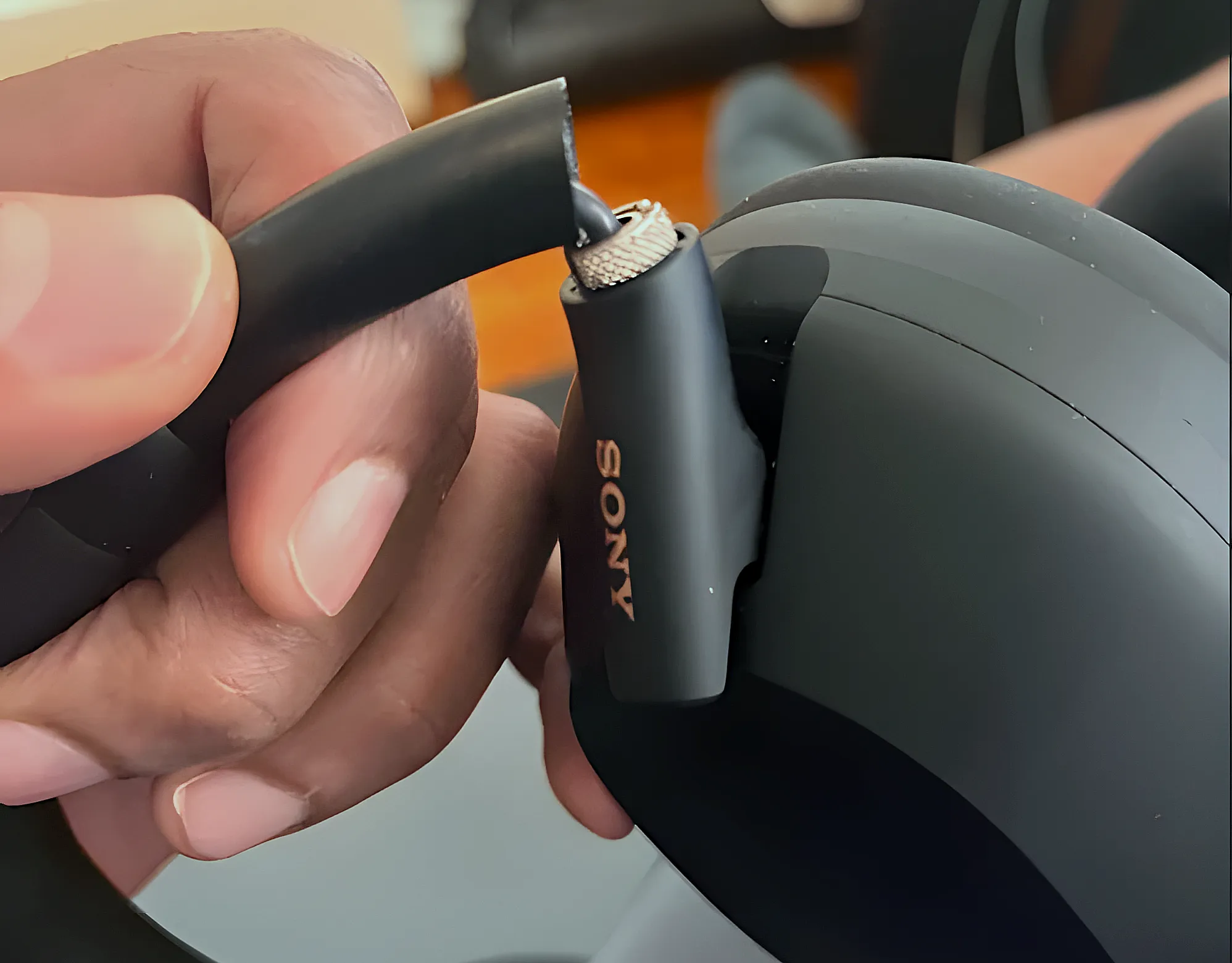 Sony WH-1000XM5: макро шарнира оголовья с видимой трещиной в пластиковом креплении чашки.