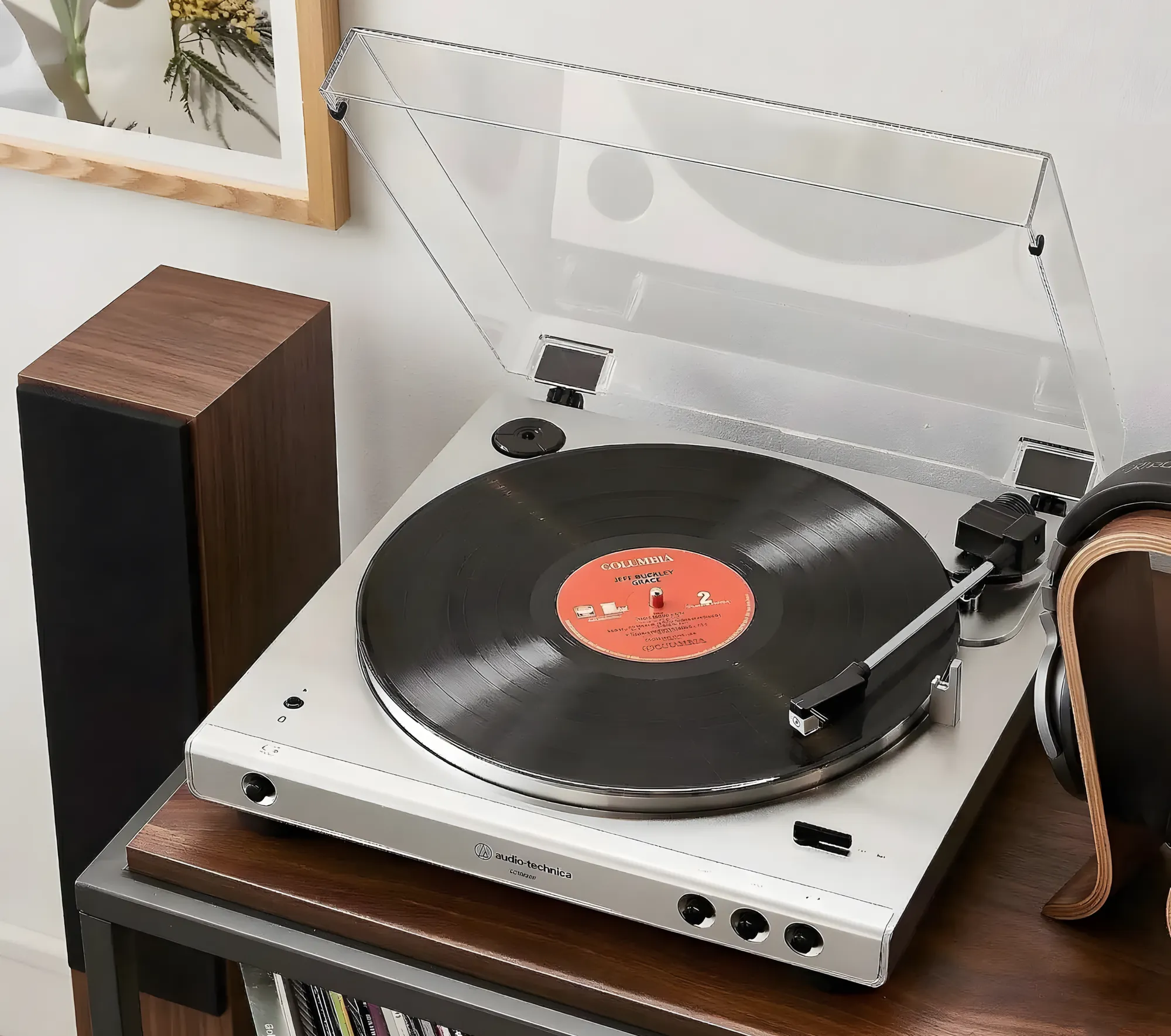 Серебристый проигрыватель Audio-Technica AT-LP60X с открытой крышкой. Видны прямой тонарм, пластинка на диске и кнопки управления на передней панели.