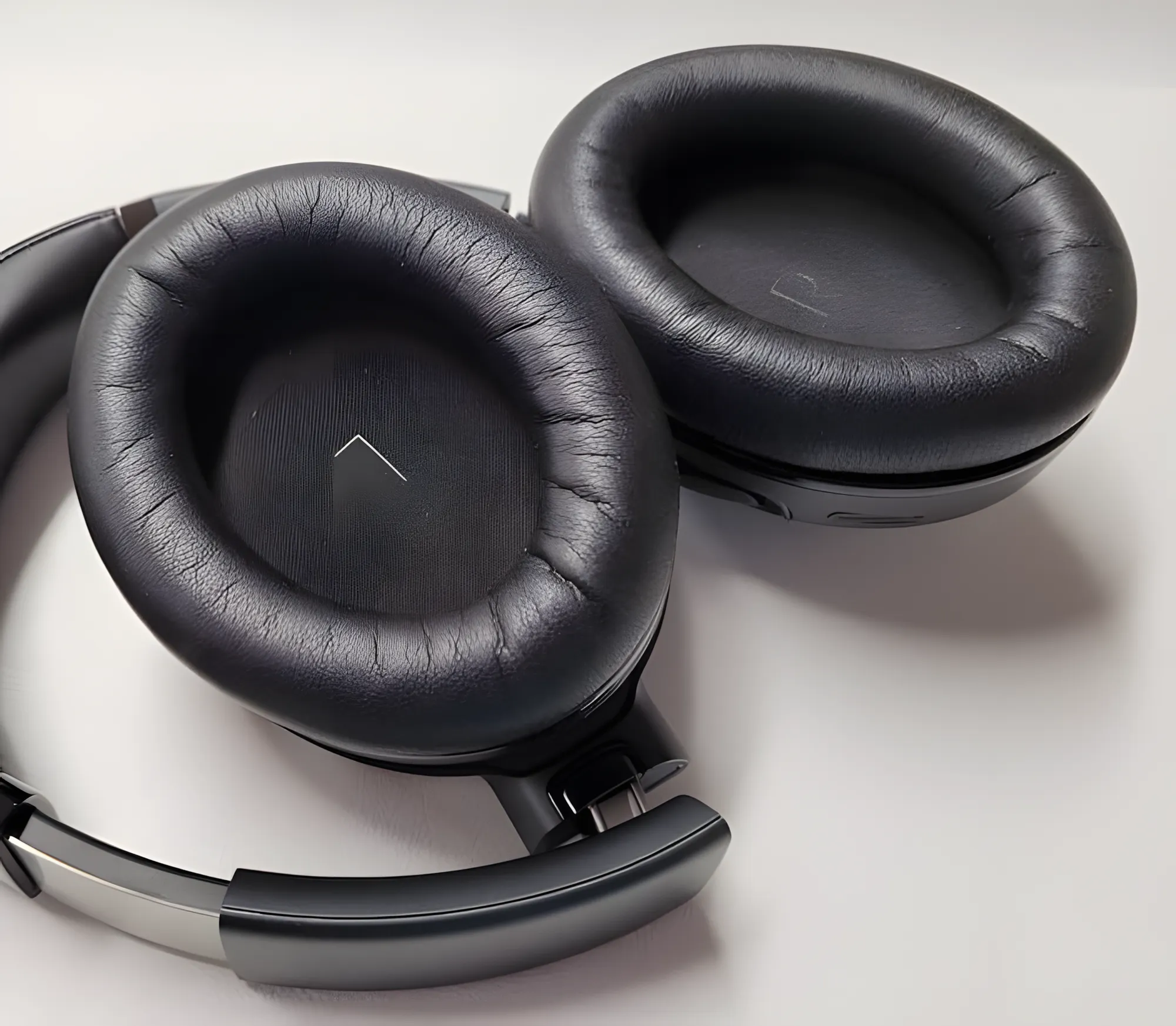 JBL Tour One M2: крупный план амбушюр с маркировкой «L» и «R», текстура кожи и оголовье, вид сверху.