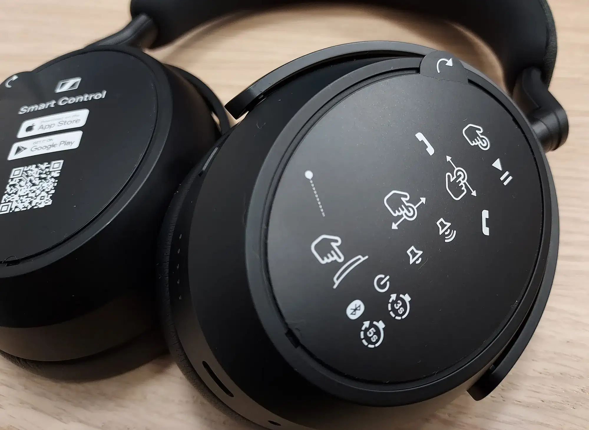 Sennheiser Momentum 4: чашки на столе с иконками жестов и QR-кодом Smart Control, крупный план, вид сверху.