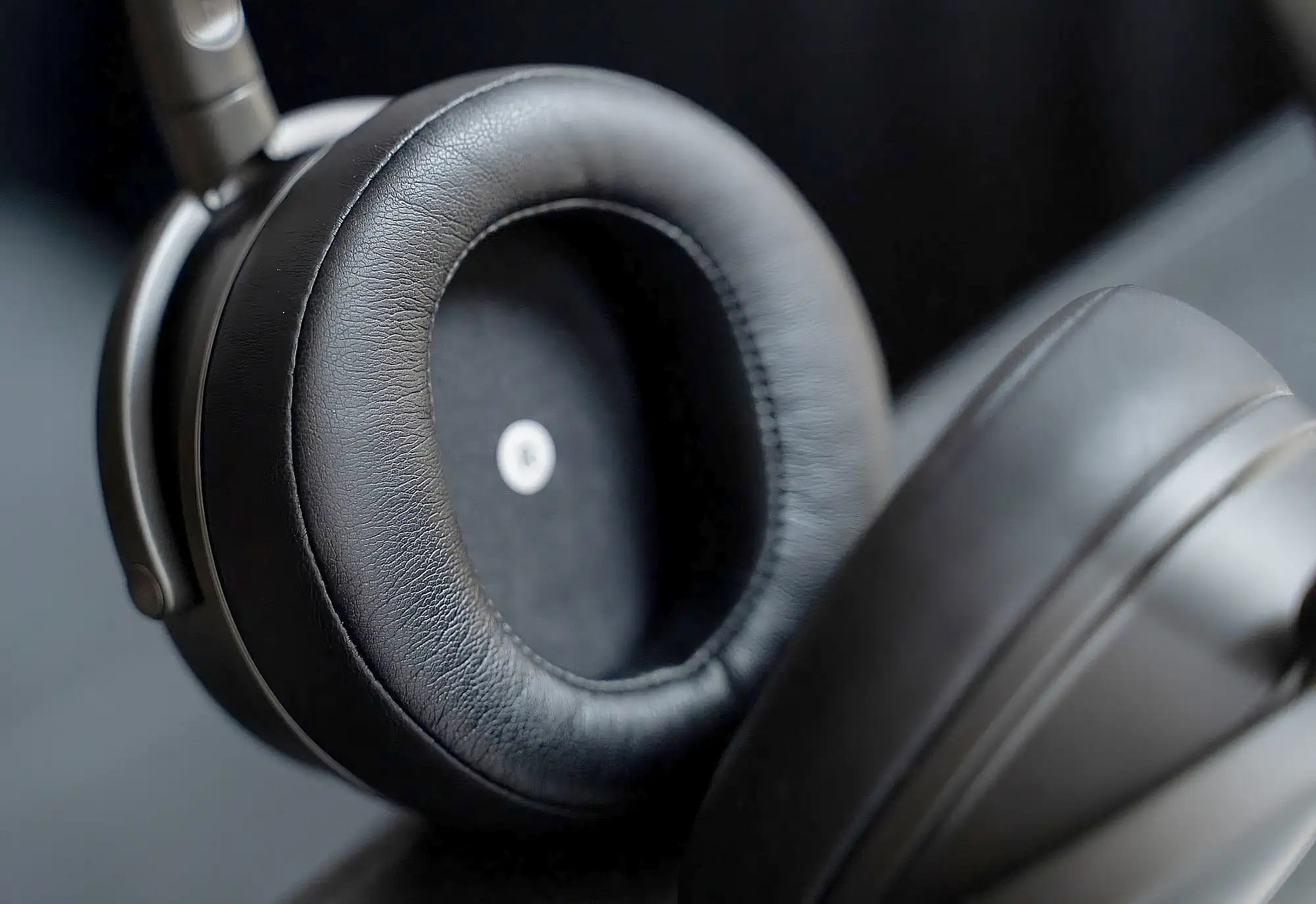 Audeze Maxwell: крупный план амбушюр, внутренняя часть с текстурой кожи и маркировкой, чашка в расфокусе.