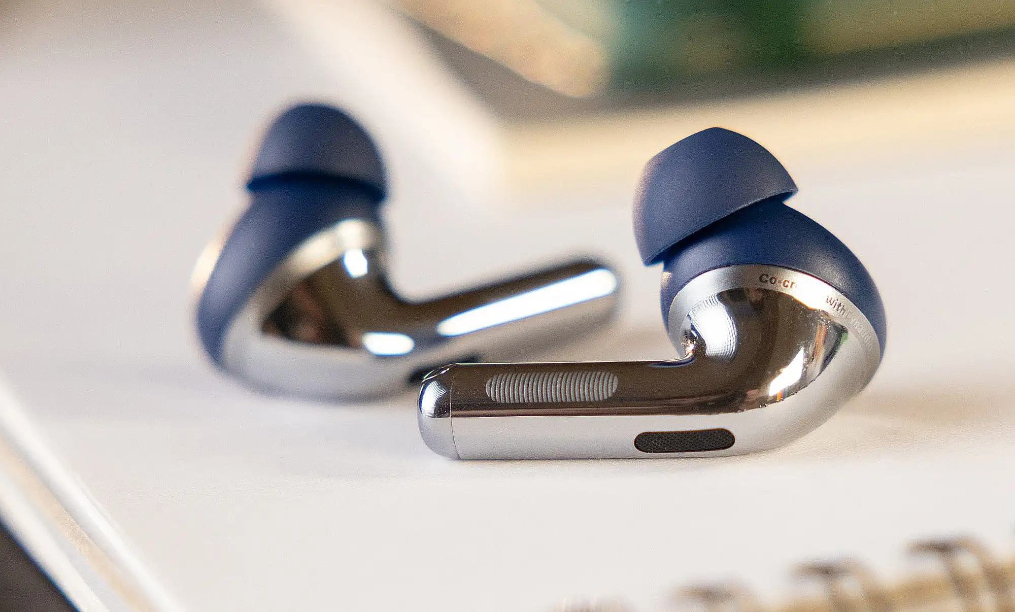 OnePlus Buds Pro 3: TWS-наушники крупным планом, матово-синий корпус и глянцевая хромированная ножка, видна сенсорная площадка.