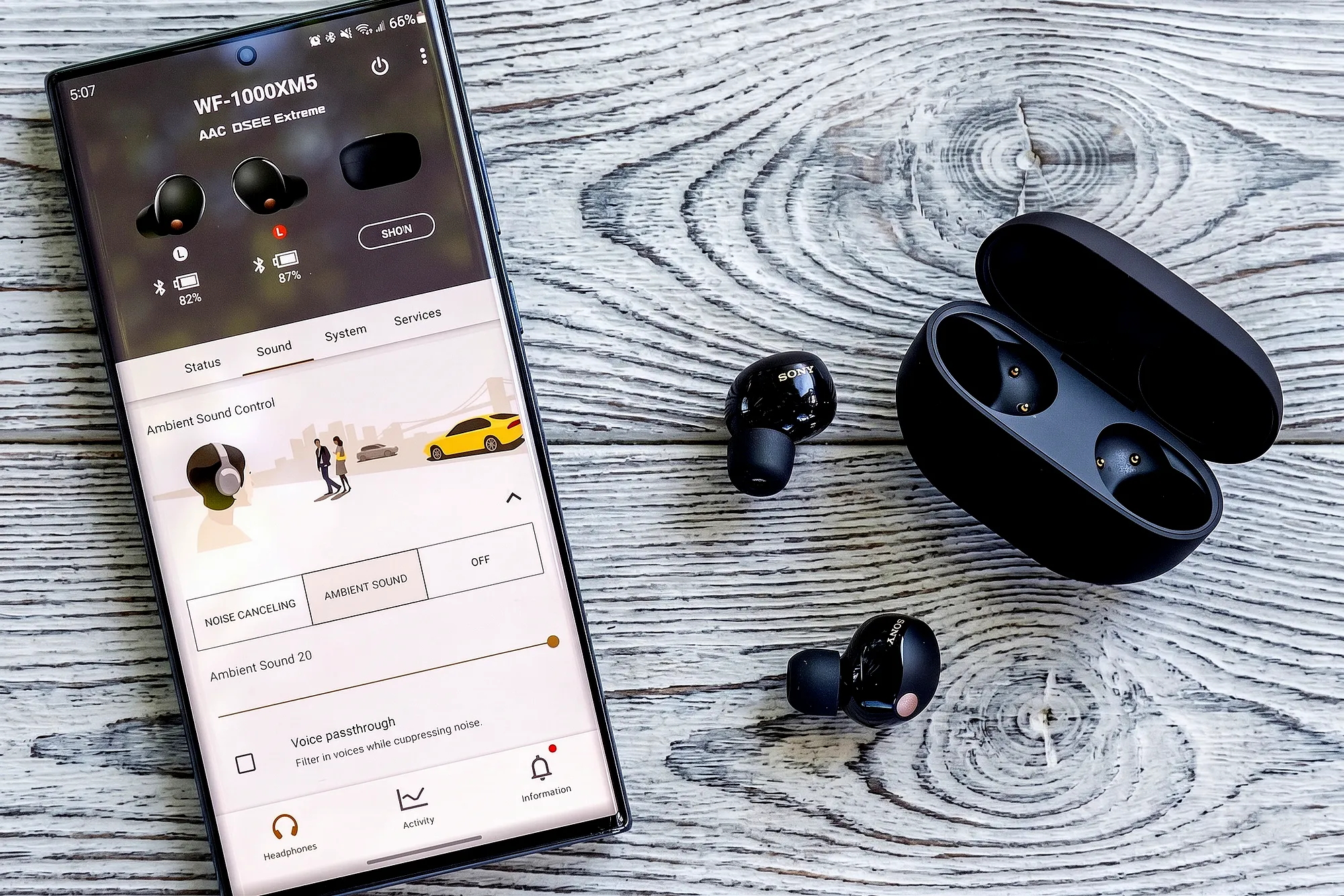 Sony WF-1000XM5: черные наушники с кейсом и смартфоном с Sound Connect, интерфейс Ambient Sound и заряд, вид сверху.
