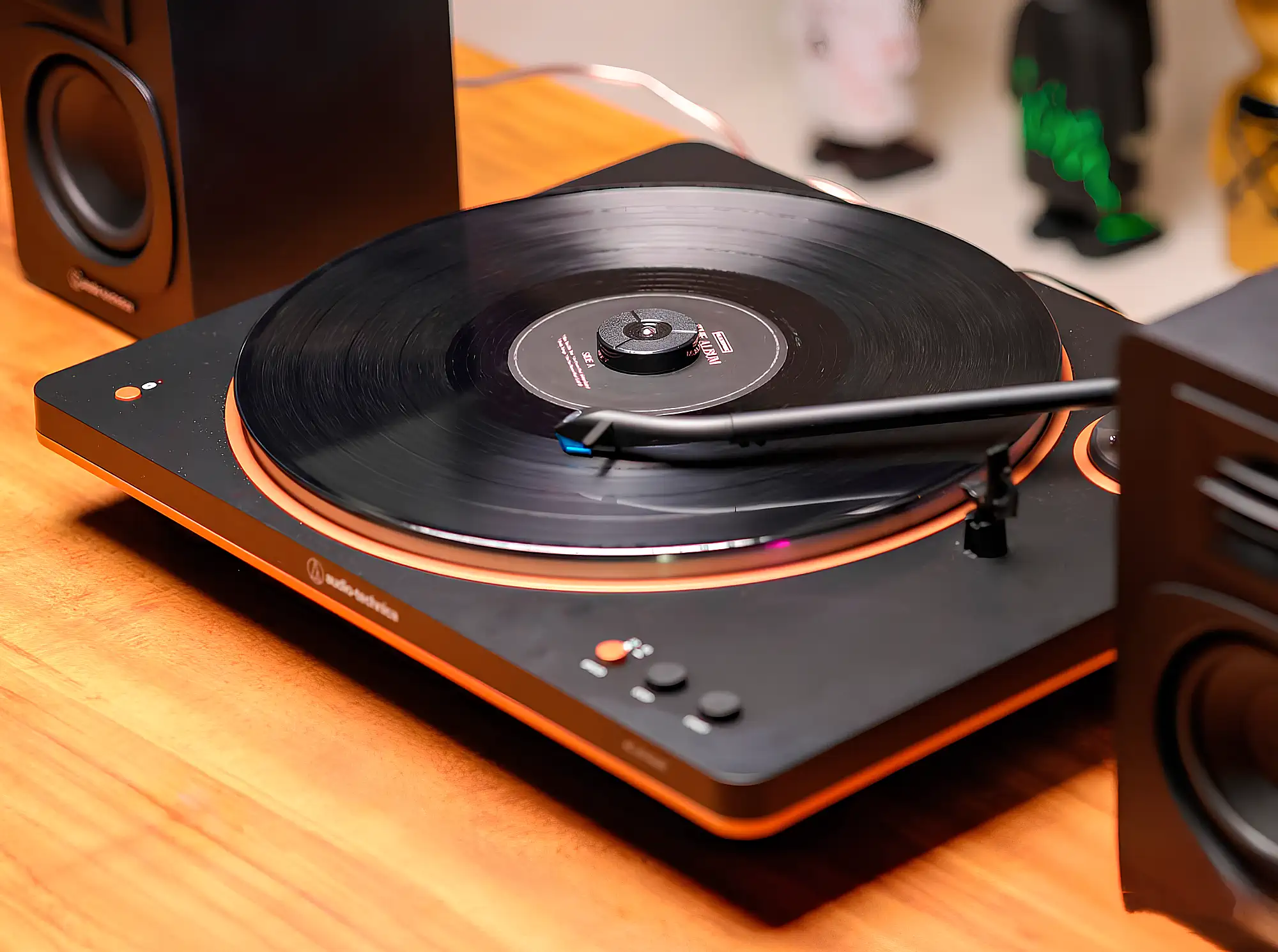Audio-Technica AT-LP70XBT: виниловый проигрыватель на столе с колонками, пластинкой и зажимом.