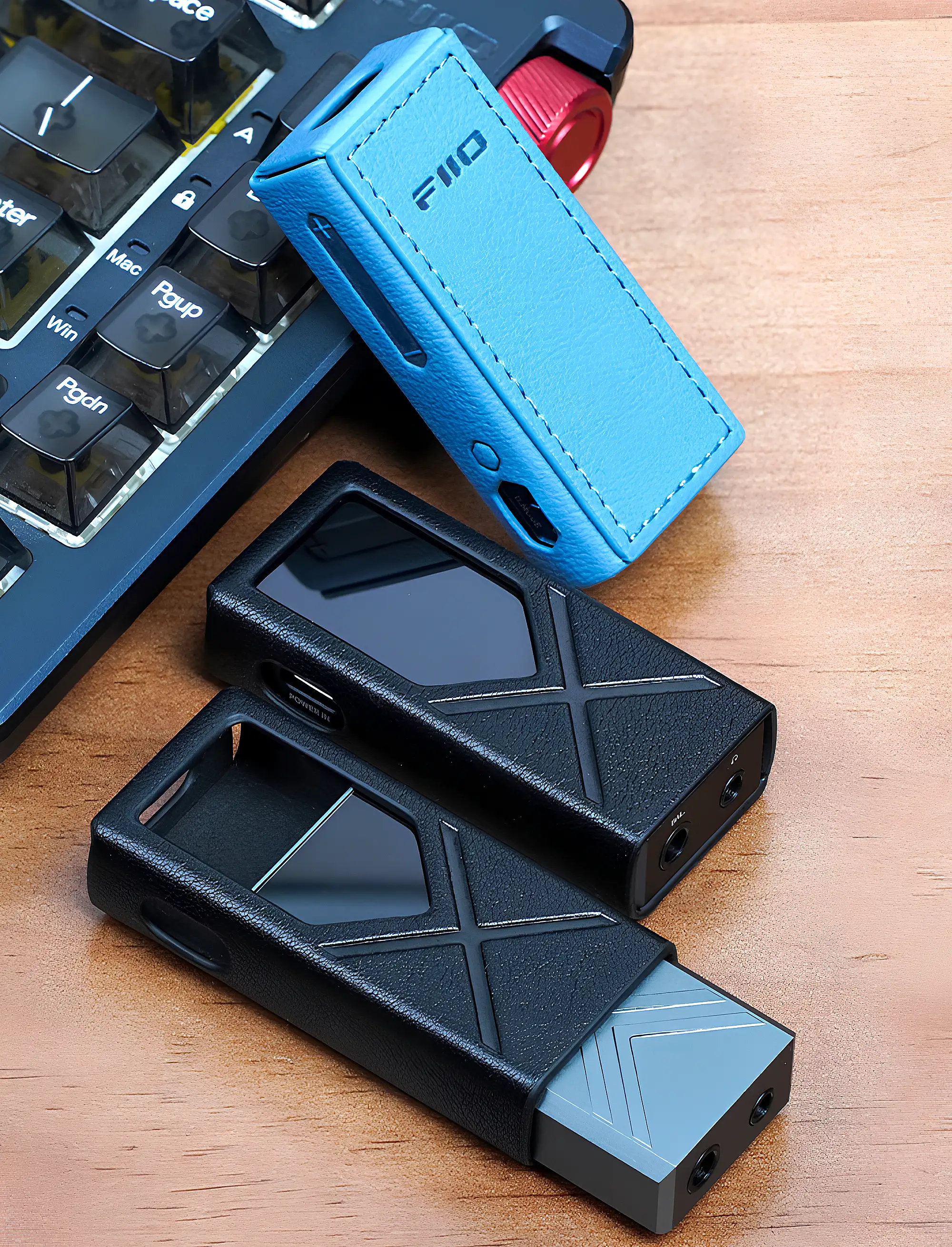 FiiO KA17: три ЦАП в чехлах на столе, вид сверху, синий и два черных, серый извлечен из нижнего.