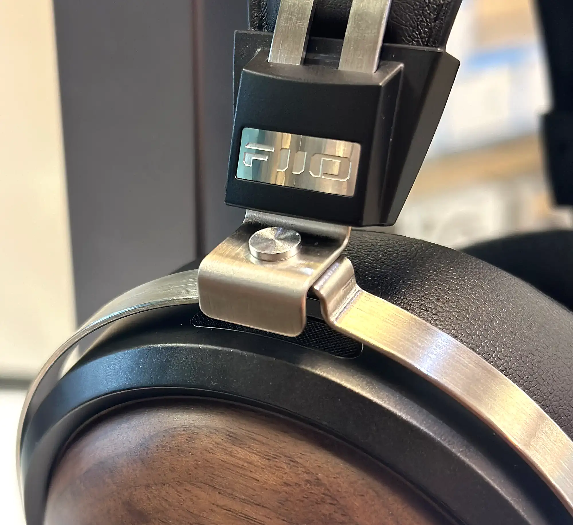 FiiO FT1: металлическое оголовье с логотипом крупным планом на размытом фоне.