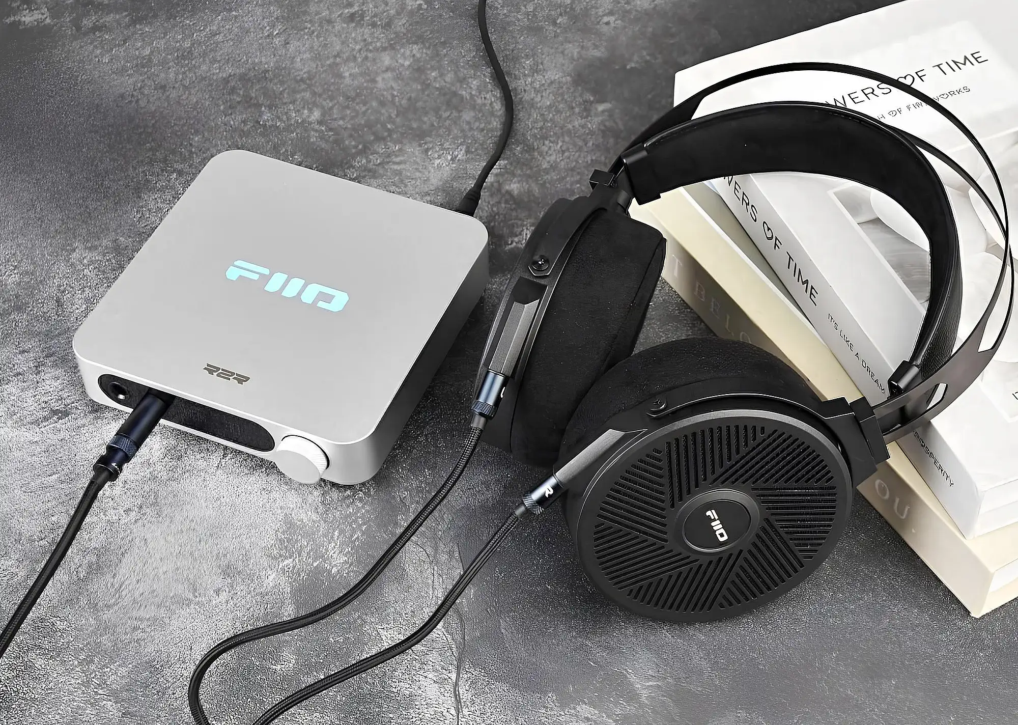 FiiO K11 R2R серебристый и FiiO FT5: наушники на столе рядом со стопкой белых книг, вид сверху.