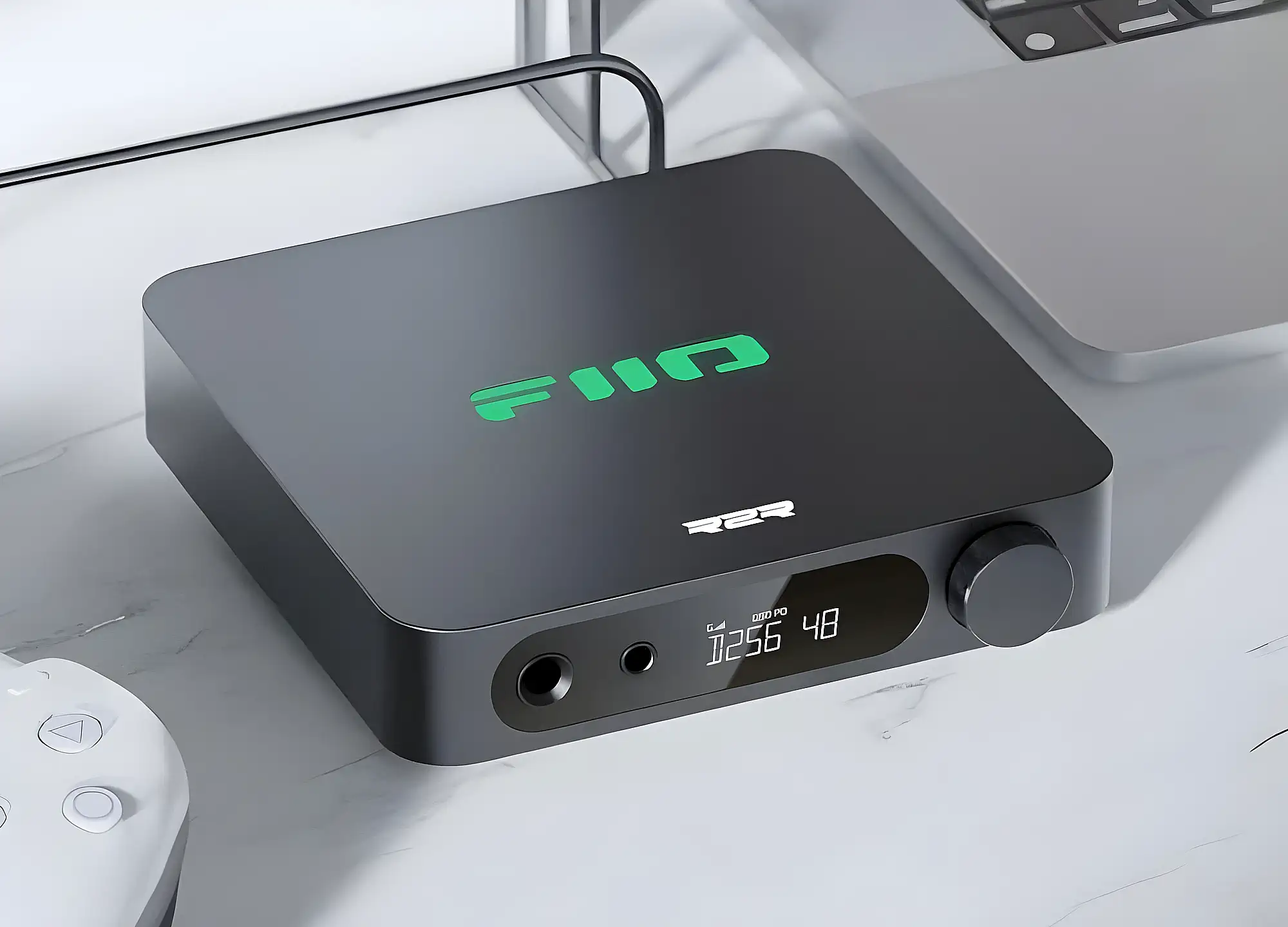 Стационарный ЦАП–усилитель FiiO K11 R2R черного цвета на светлом столе. Вид сверху на корпус со светящимся зеленым логотипом бренда.