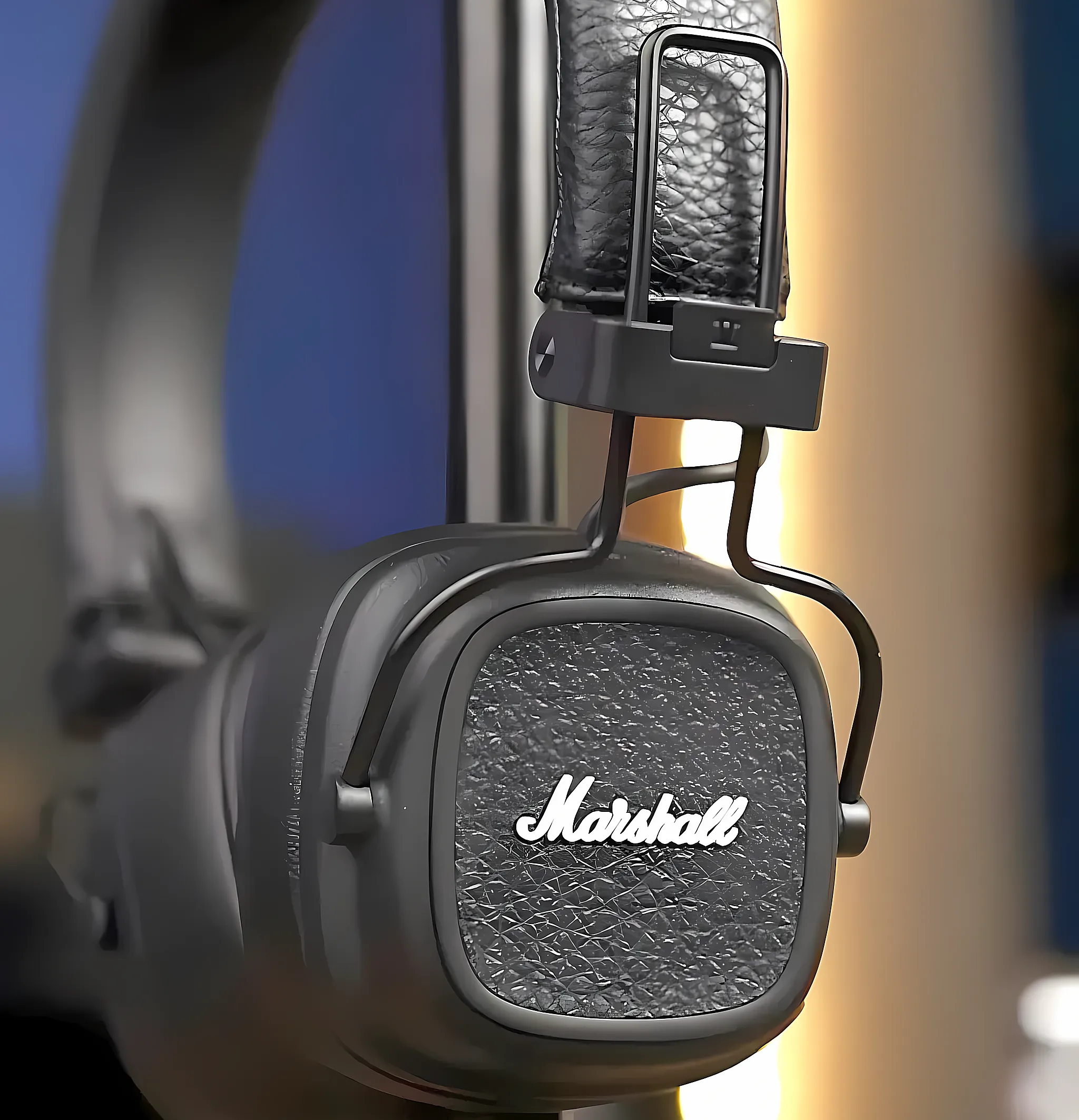 Крупный план чашки наушников Marshall Major V: рельефная текстура экокожи, белый логотип бренда и крепление оголовья.