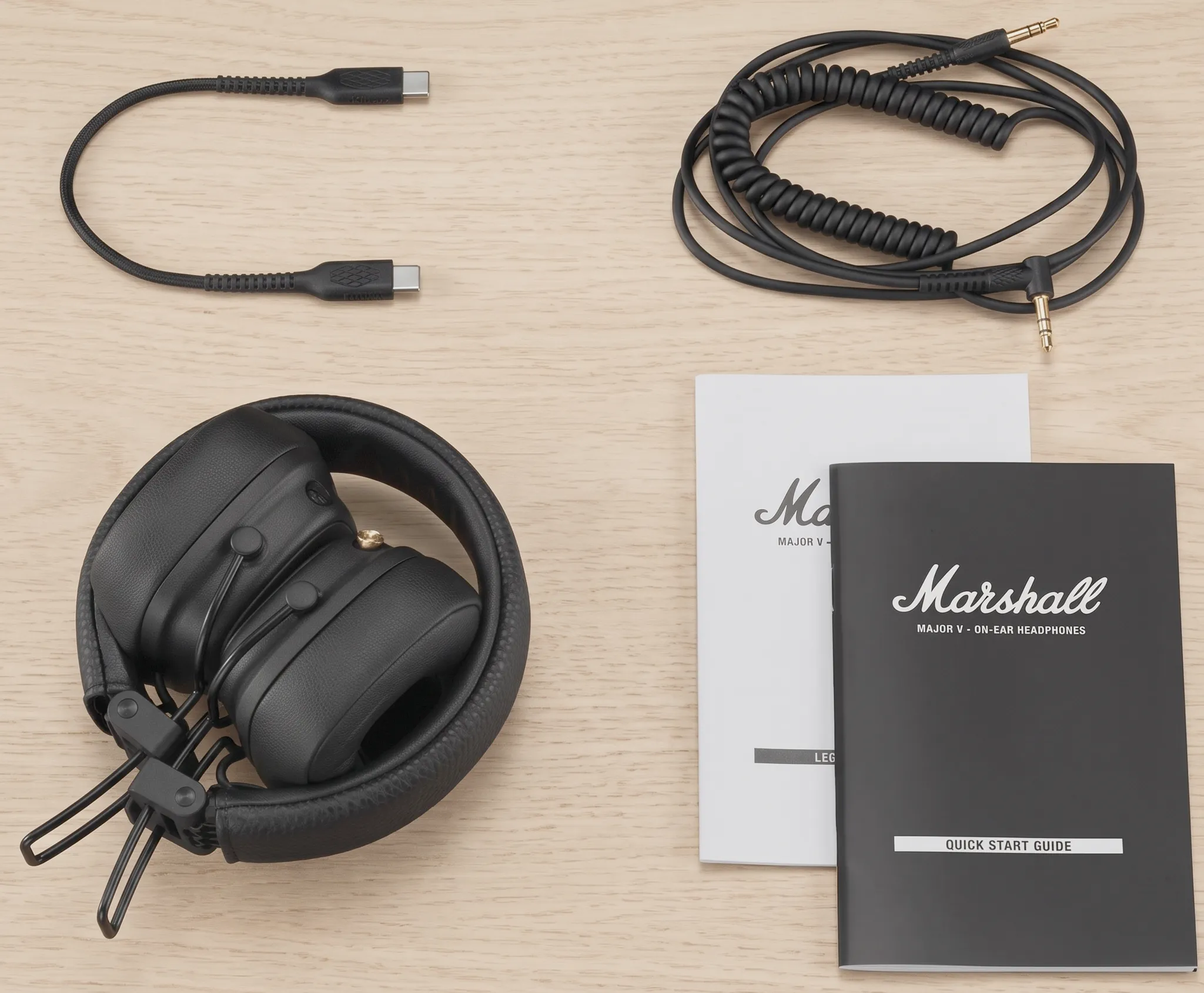 Комплект поставки Marshall Major V: наушники, кабель Type-C, витой аудиокабель 3,5 мм и документация на столе.