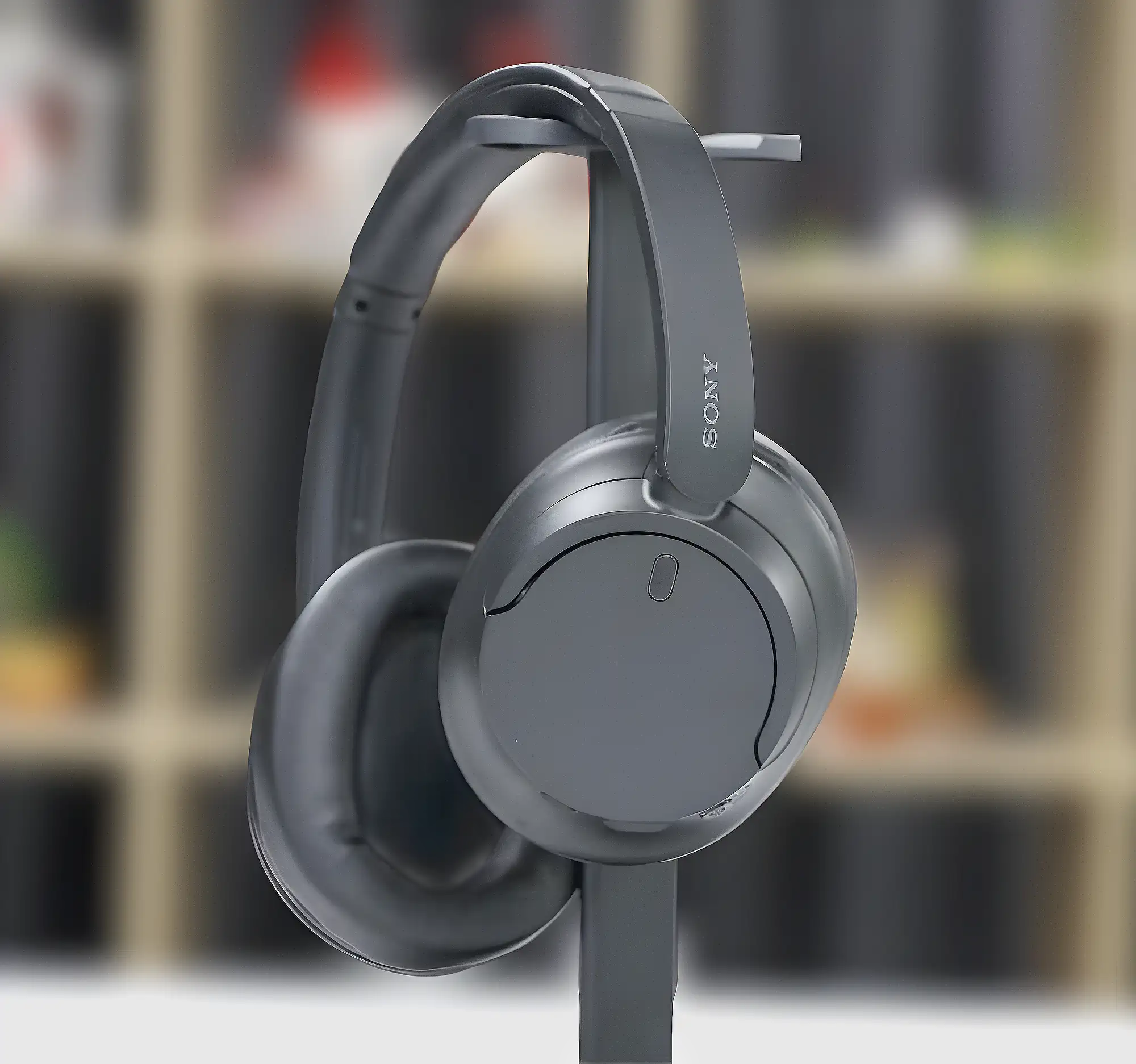 Sony WH-CH720N: серые полноразмерные наушники на стойке, овальная чашка с логотипом, крупный план.