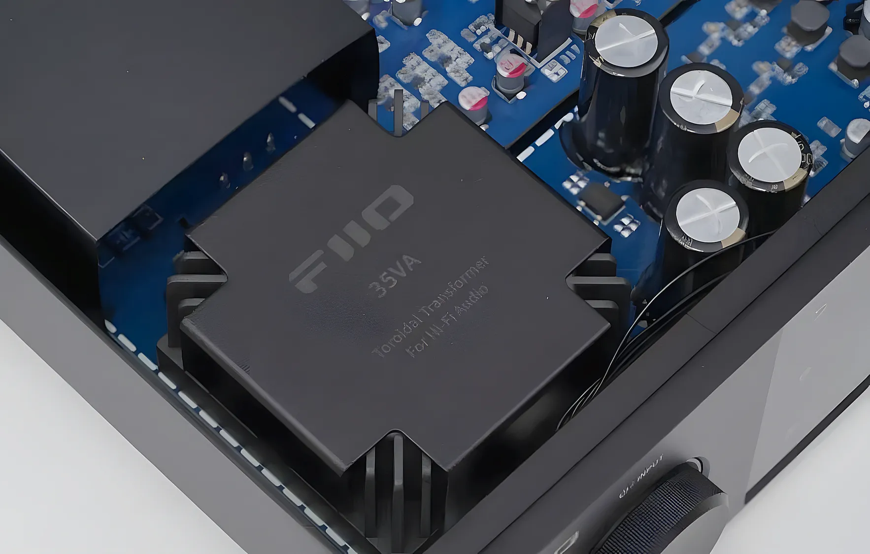 Тороидальный трансформатор блока питания FiiO S15. Крупный план внутренней платы с конденсаторами.