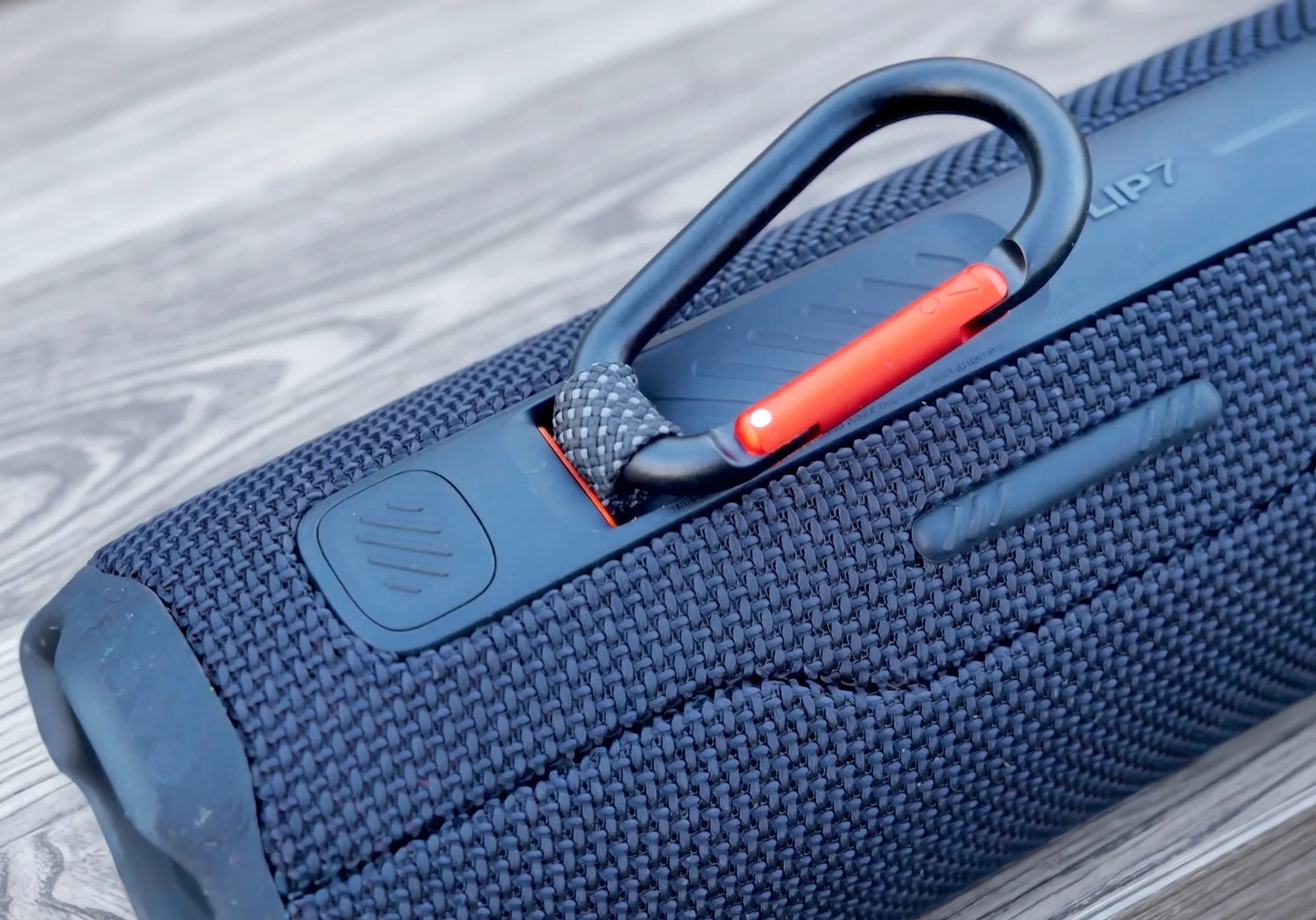 Система крепления PushLock на колонке JBL Flip 7. Крупный план карабина, закрепленного в пазу корпуса.