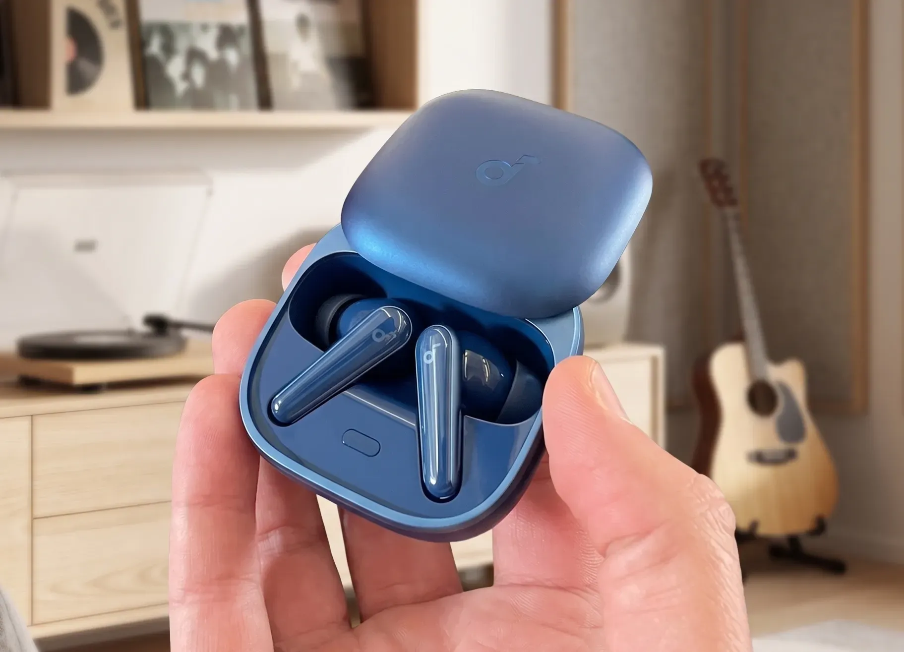 TWS-наушники Soundcore Liberty 5 в синем кейсе в руке. Крупный план открытого футляра.