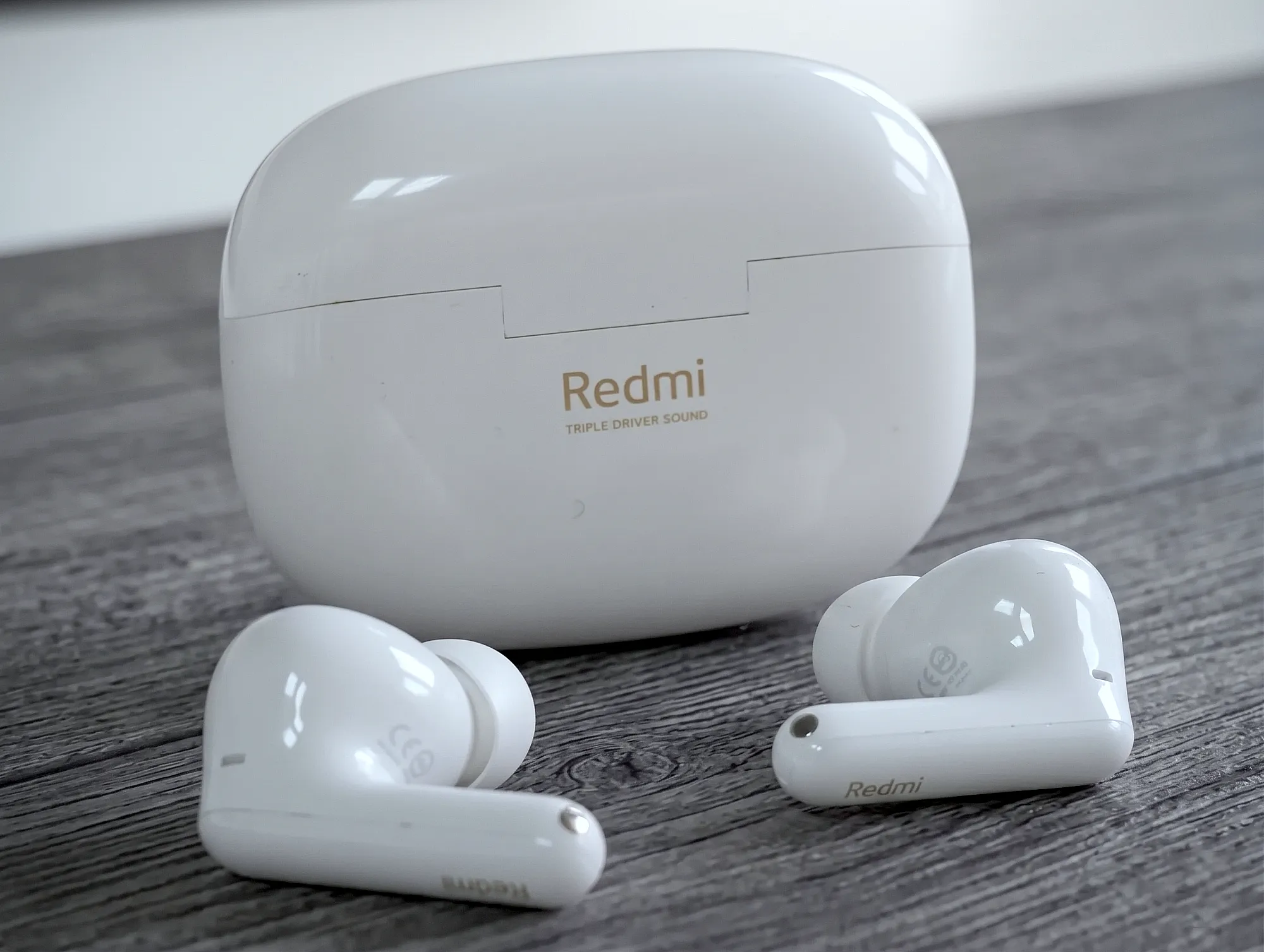 TWS–наушники Redmi Buds 6 Pro белого цвета перед закрытым зарядным кейсом.