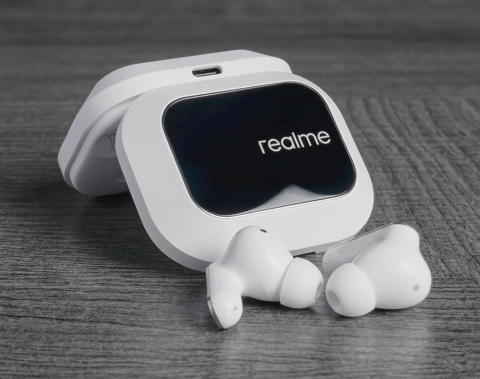 TWS–наушники Realme Buds Air 8 Pro белого цвета перед зарядным кейсом с черной глянцевой вставкой и логотипом.