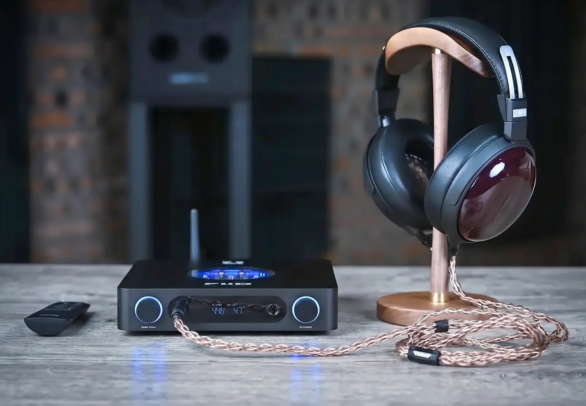 Усилитель для наушников и ЦАП FiiO K13 R2R на столе рядом с полноразмерными наушниками на деревянной подставке.