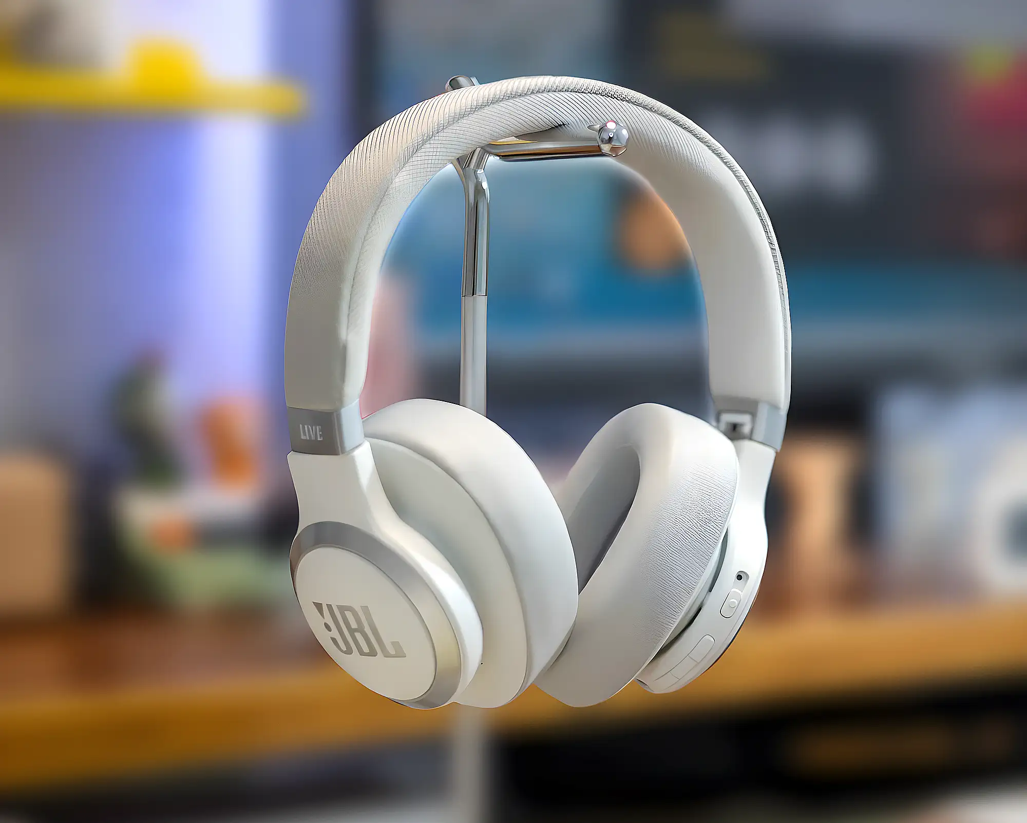Наушники JBL Live 770NC белого цвета на стойке с тканевым оголовьем и круглыми чашками.