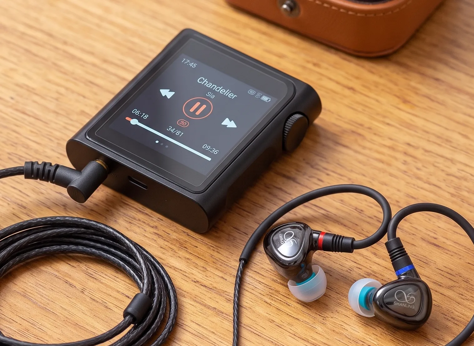 Цифровой черный миниатюрный плеер Shanling M0 Pro и IEM наушники Shanling ME80 на деревянном столе.