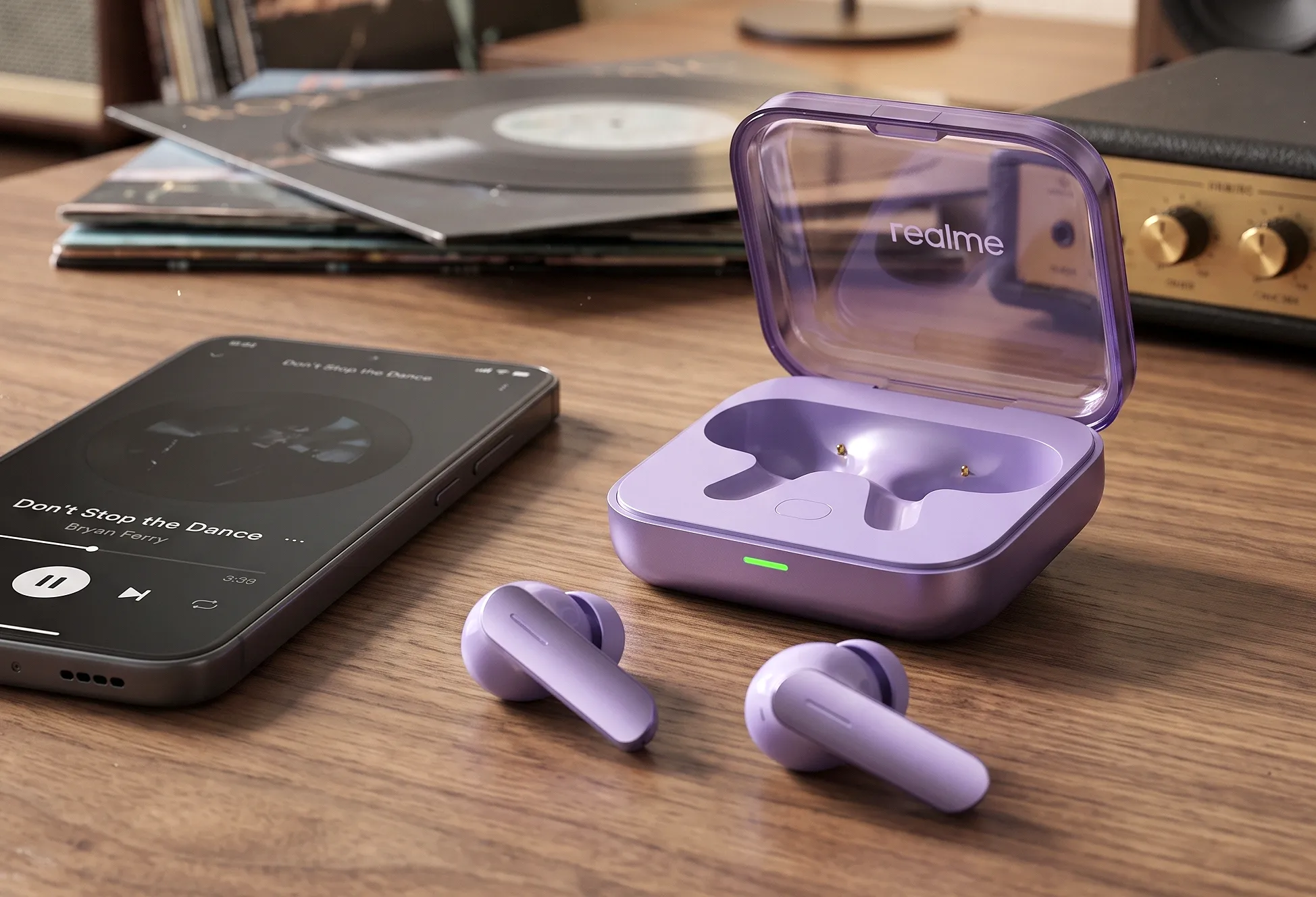 Сиреневые TWS-наушники Realme Buds Air 7 рядом с открытым зарядным кейсом и смартфоном на деревянном столе.
