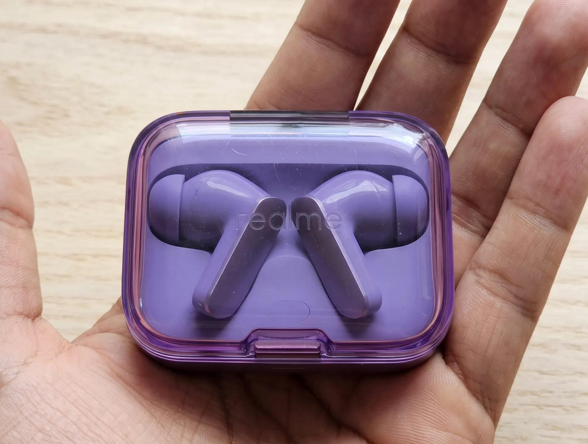 Фиолетовый зарядный кейс наушников Realme Buds Air 7 с прозрачной крышкой на открытой ладони.
