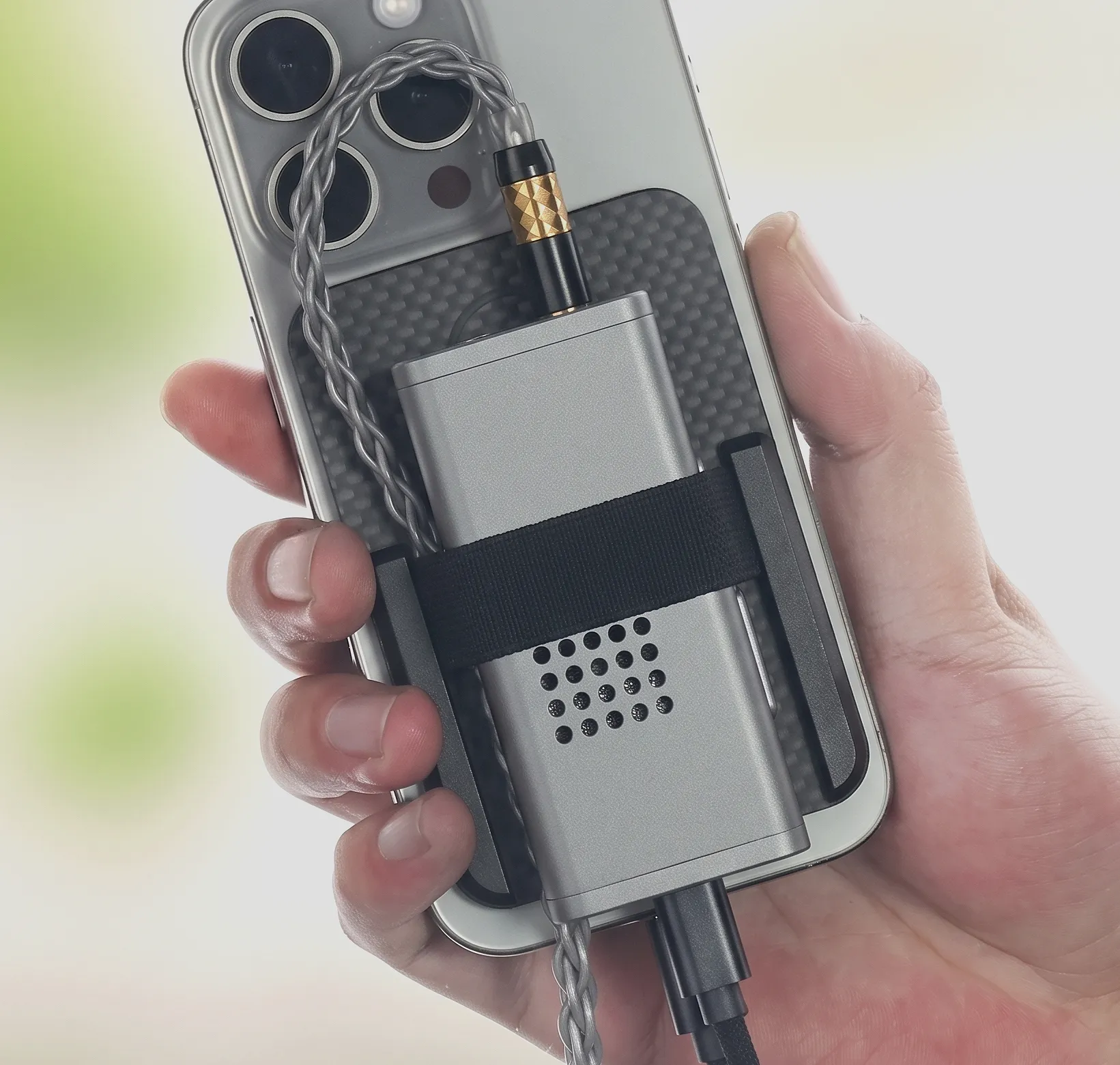 Донгл Moondrop Dawn Pro 2 прикрепленный к спинке смартфона стяжкой с аккуратно изогнутым и не натянутым кабелем.