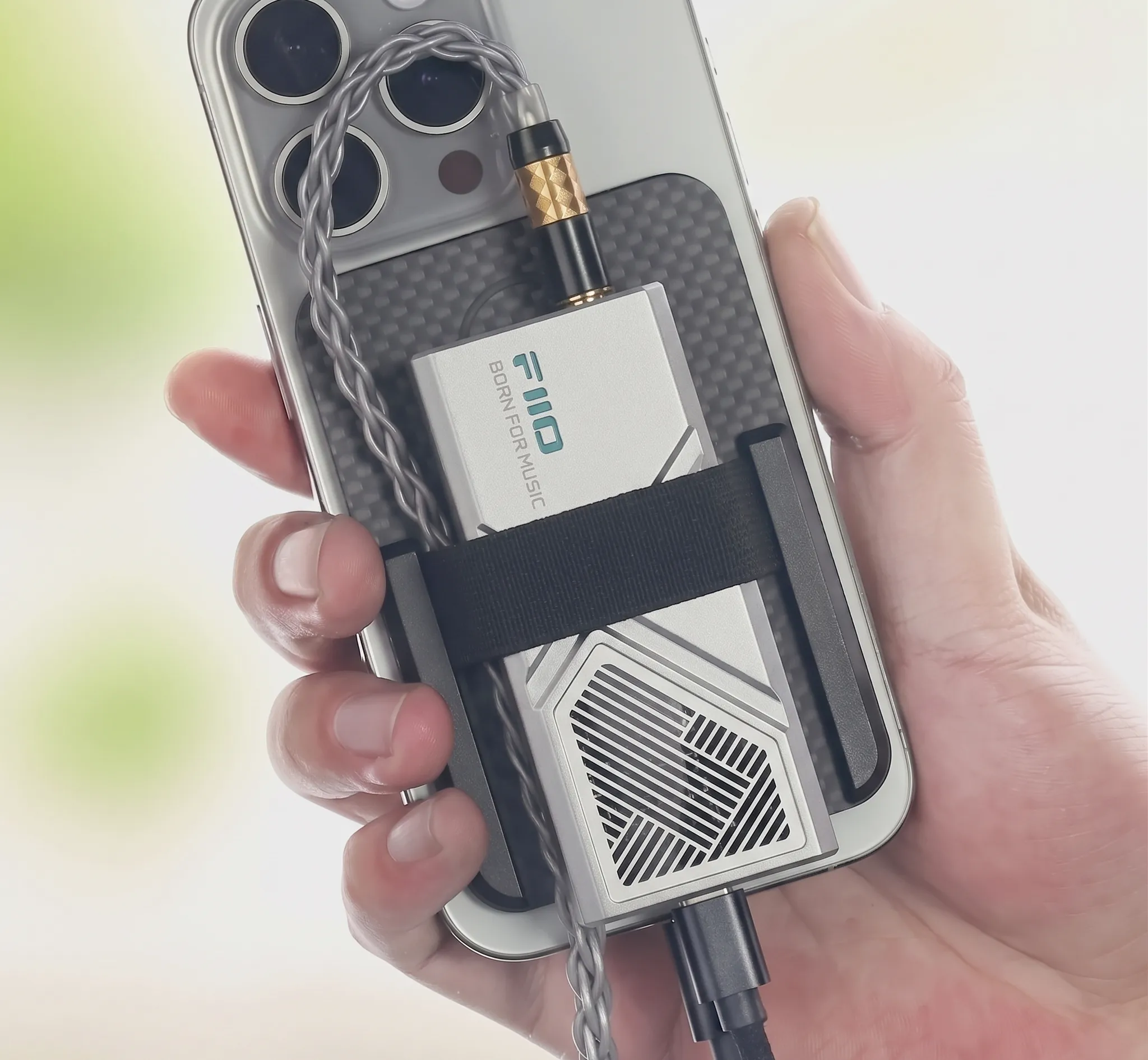 Донгл FiiO KA13 прикрепленный к спинке смартфона стяжкой с аккуратно изогнутым и не натянутым кабелем.