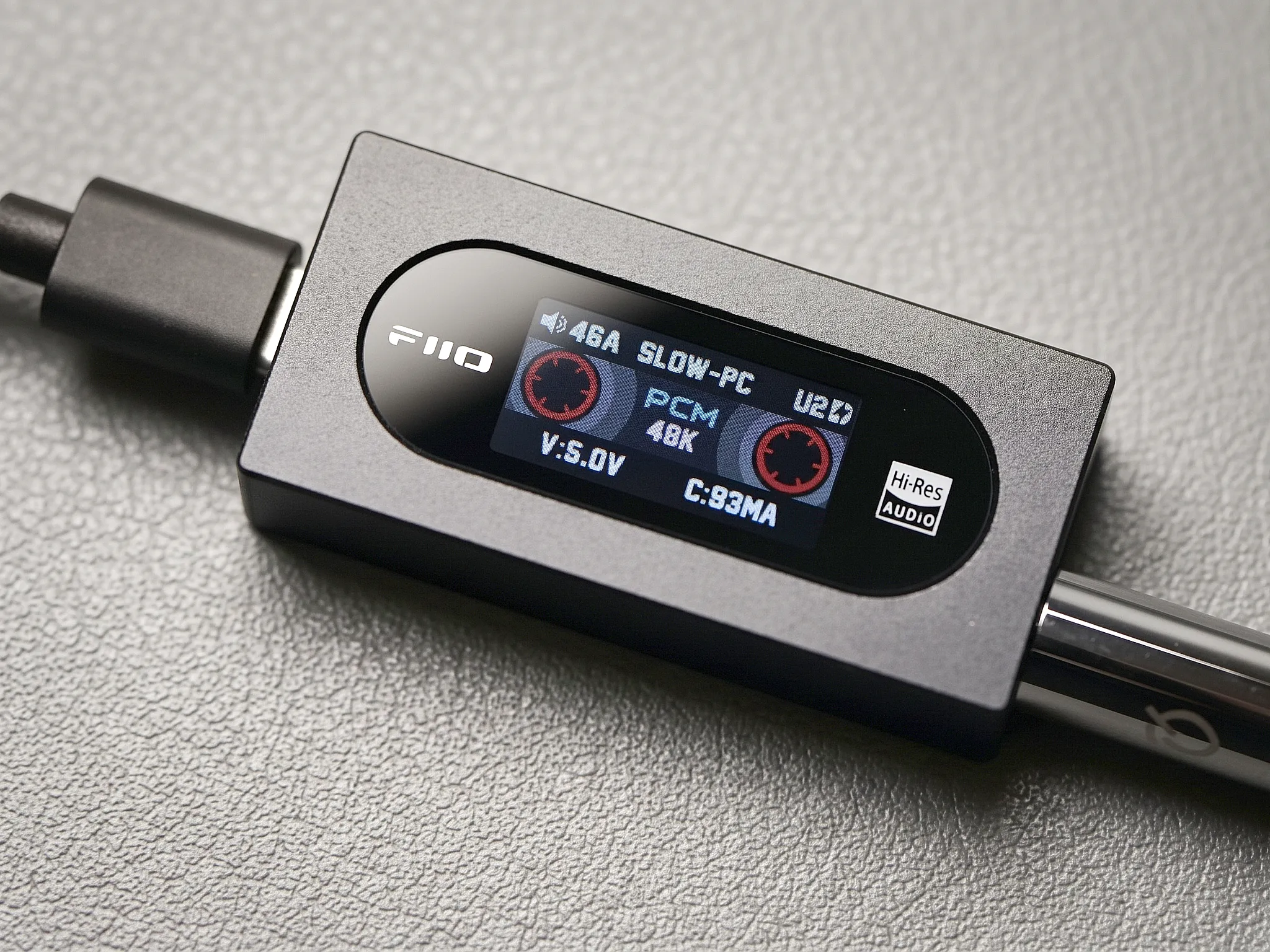 Портативный ЦАП-усилитель FiiO KA15 с активным цветным экраном в ретро-стиле кассеты, подключенными кабелями питания и наушников.