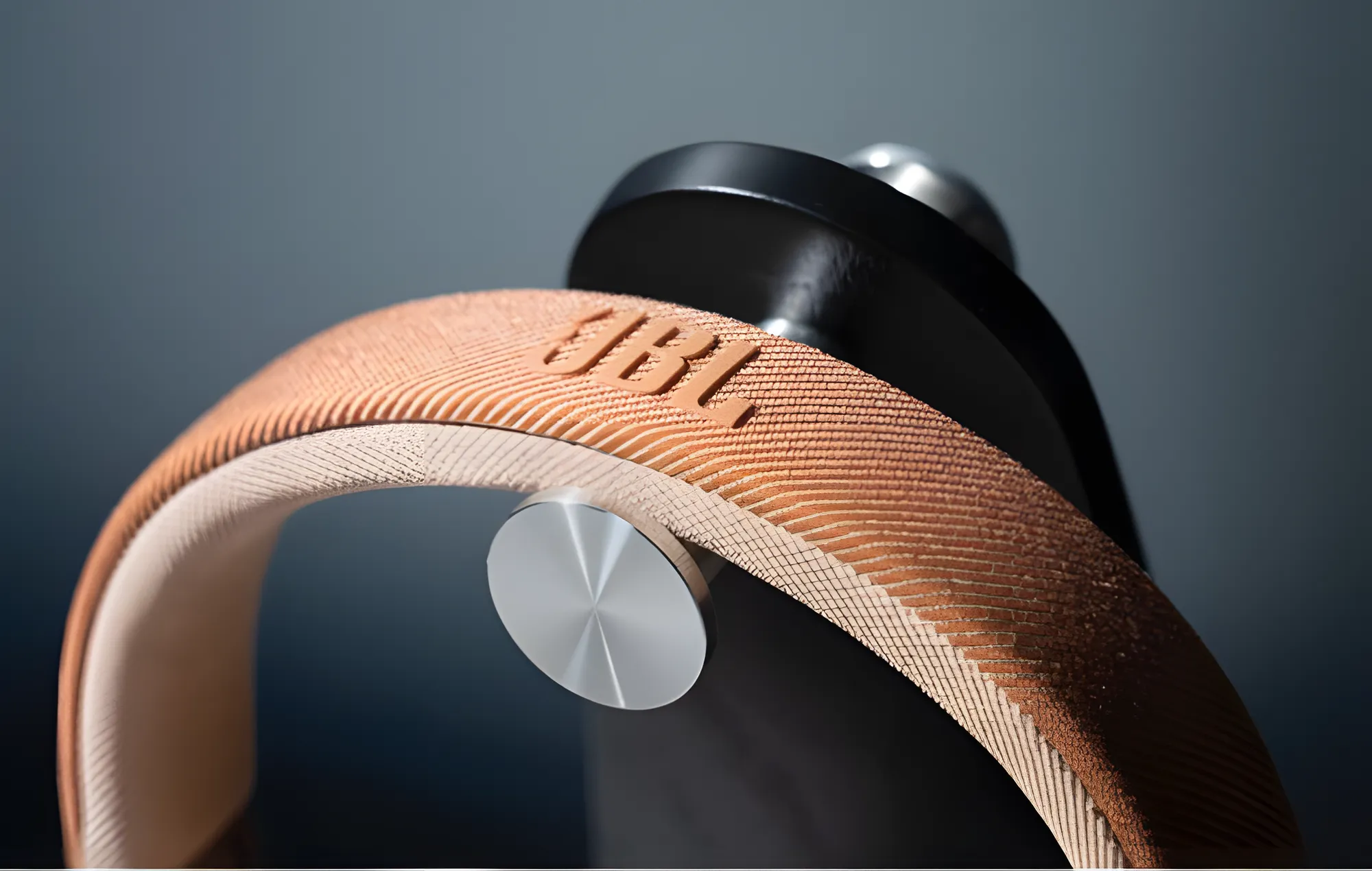 Тканевое оголовье JBL Live 770NC с фирменным логотипом крупным планом на темном фоне.