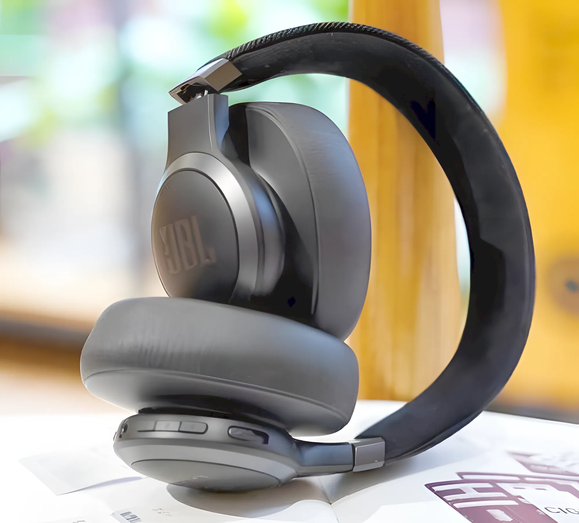 Складная конструкция наушников JBL Live 770NC: сложенный девайс на белой поверхности.