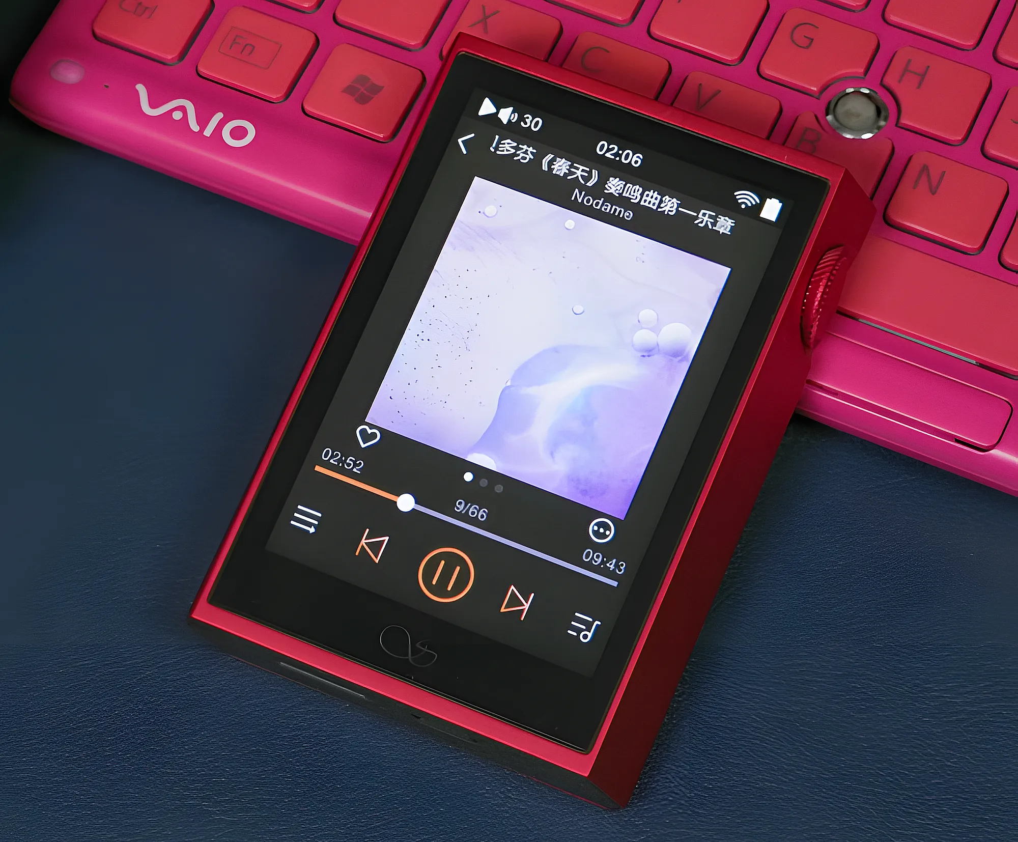 Плеер Shanling M1 Plus рядом с клавиатурой VAIO: экран с обложкой альбома и колесо громкости.
