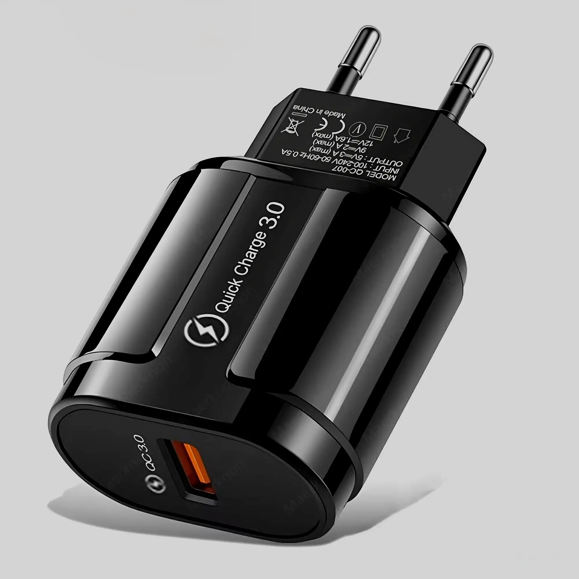 Черное сетевое зарядное устройство с поддержкой Quick Charge 3.0, один оранжевый USB‑порт на торце, двухштырьковая вилка, предмет снят крупным планом на сером фоне.